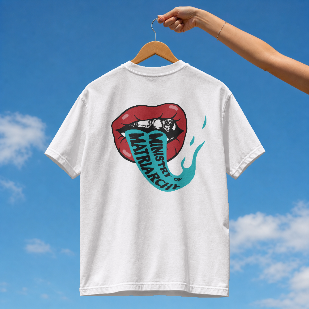 Ministry of Matriarchy box tee in white on a hanger against blue sky, back view with red lips and snake tongue print