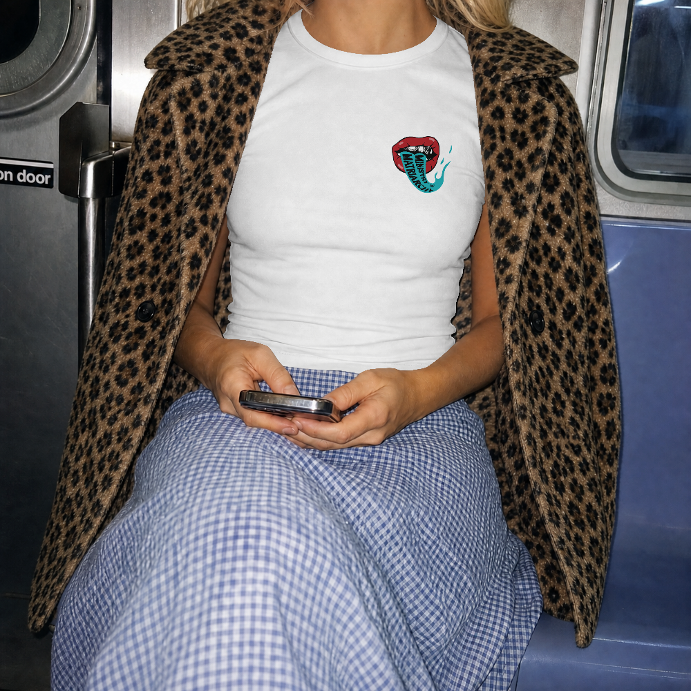 Ministry of Matriarchy box tee in white worn by a model with a leopard print coat, front view with small lips chest print